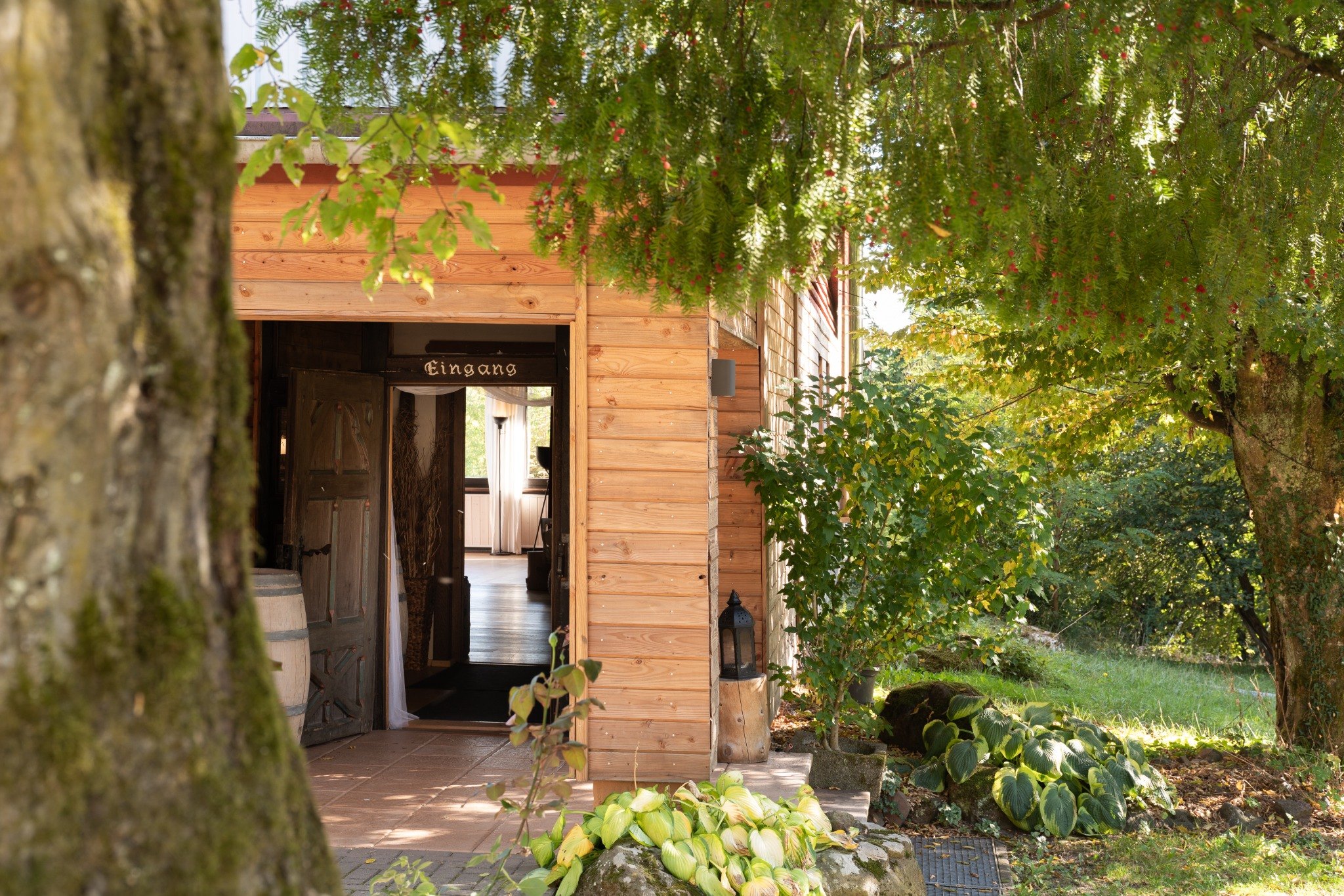Eingang und Holzfassade zwischen grünen Bäumen