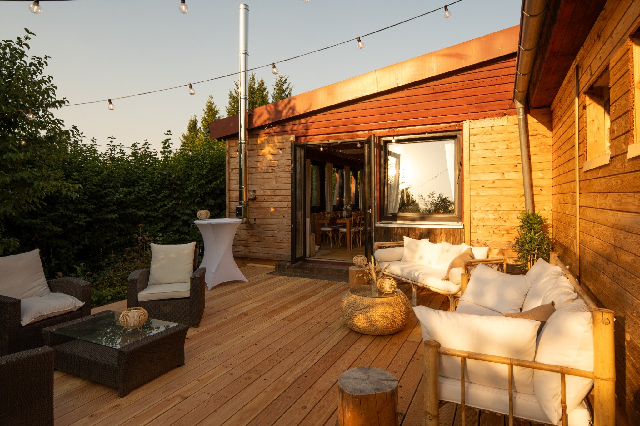 Holzterrasse mit Lounge-Möbeln und Lichterketten